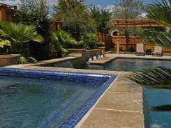 Iridescent Glass Tile Spa, Brass Spillways with Ocean Blue Pebble Sheen in Allen