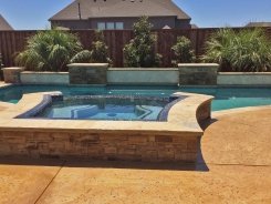 Iridescent Glass Tile Spa with Aqua Blue Pebble Sheen Raised Bond Beam in Prosper