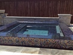 Iridescent Glass Tile Perimeter Overflow Spa with Blue Granite Pebble Sheen in Frisco