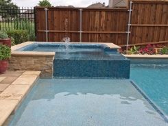 Iridescent Glass Tile Spa with Aqua Blue Pebble Sheen and Tanning Ledge in Frisco